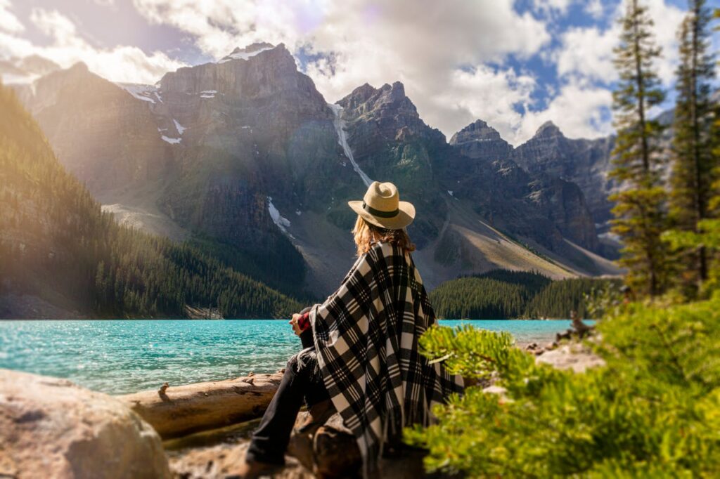 Woman sitting peacefully while looking at mountain landscape, symbolizing healing and reflection on the trauma and physical health connection.